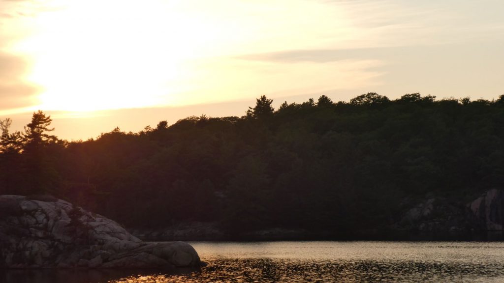 the sun setting above the rock outcropping that we dubbed the dolphin's nose at George Lake in Killarney Provincial Park