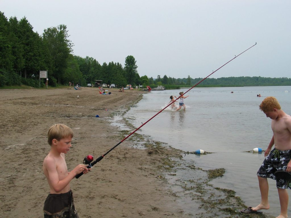 picture of a young boy with a fishing rod fishing on the beach at Emily Provincial Park