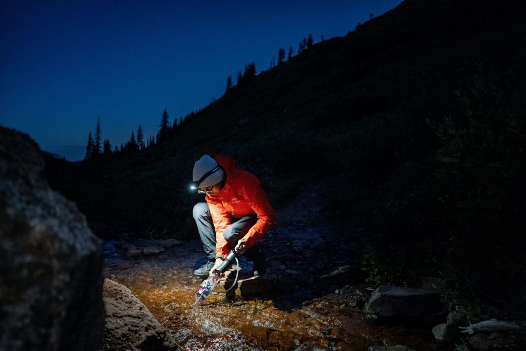 picture of a woman using water filters to clean her drinking water while backcountry camping