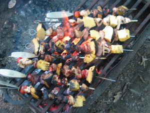 picture of kebabs on skewers cooking over a campfire for lunch while camping
