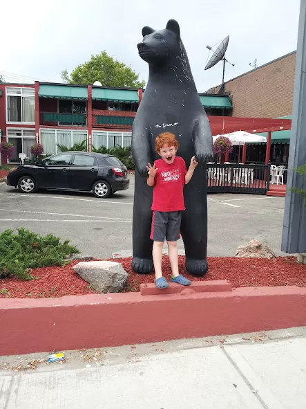 picture of a boy in front of a bear statue pretending to be afraid of the bear