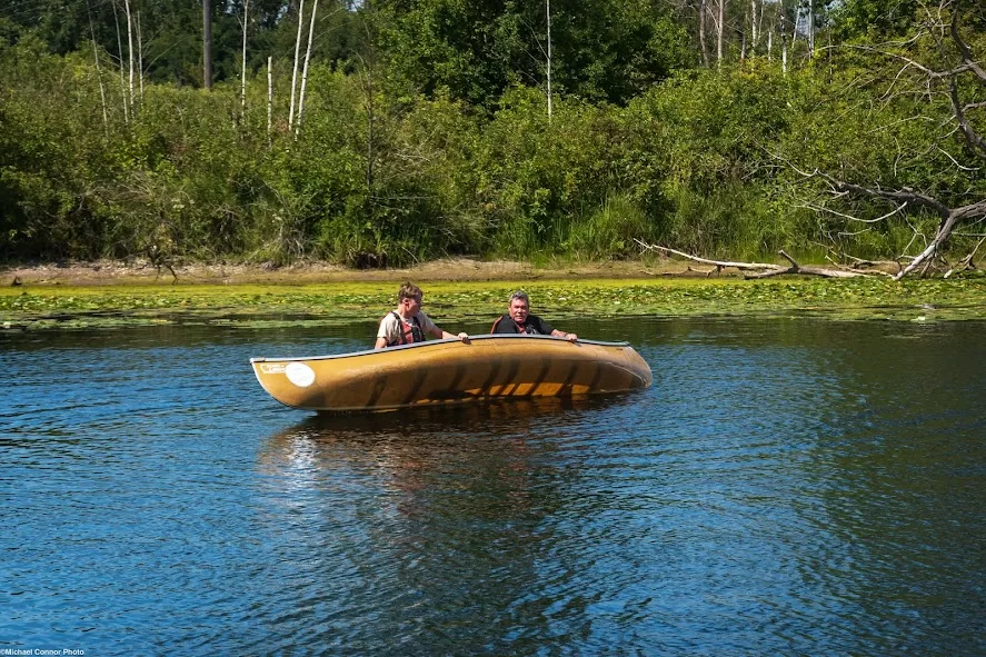 picture of two people trying to flip a canoe back over after it tipped and empty the water out of it