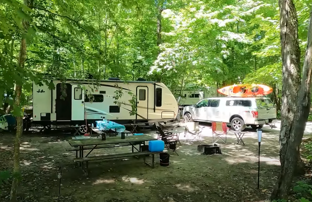 picture of a provincial park campsite with a travel trailer, pickup truck, and kayak from Ben and Cheryl Coles, of Camping with the Coles