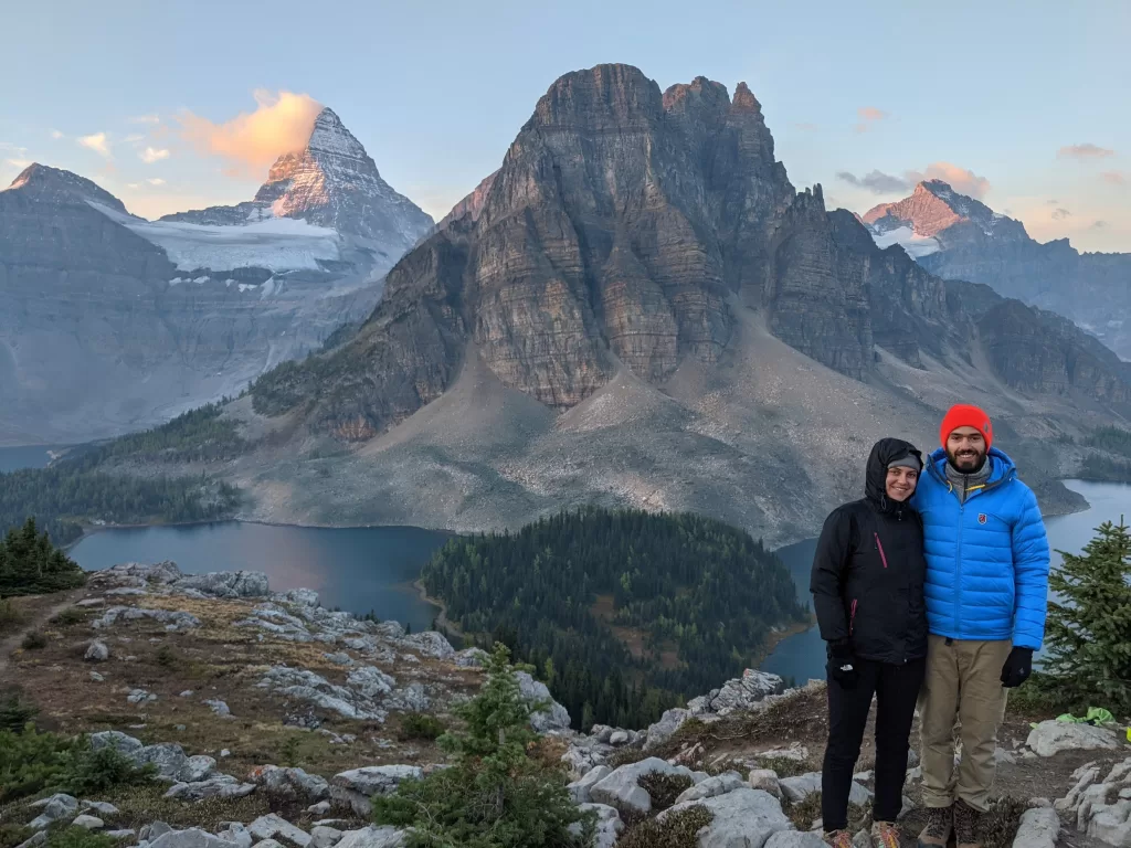 picture of a woman and a man taking an epic hike on the Assiniboine trail with Mount Assiniboine in the background