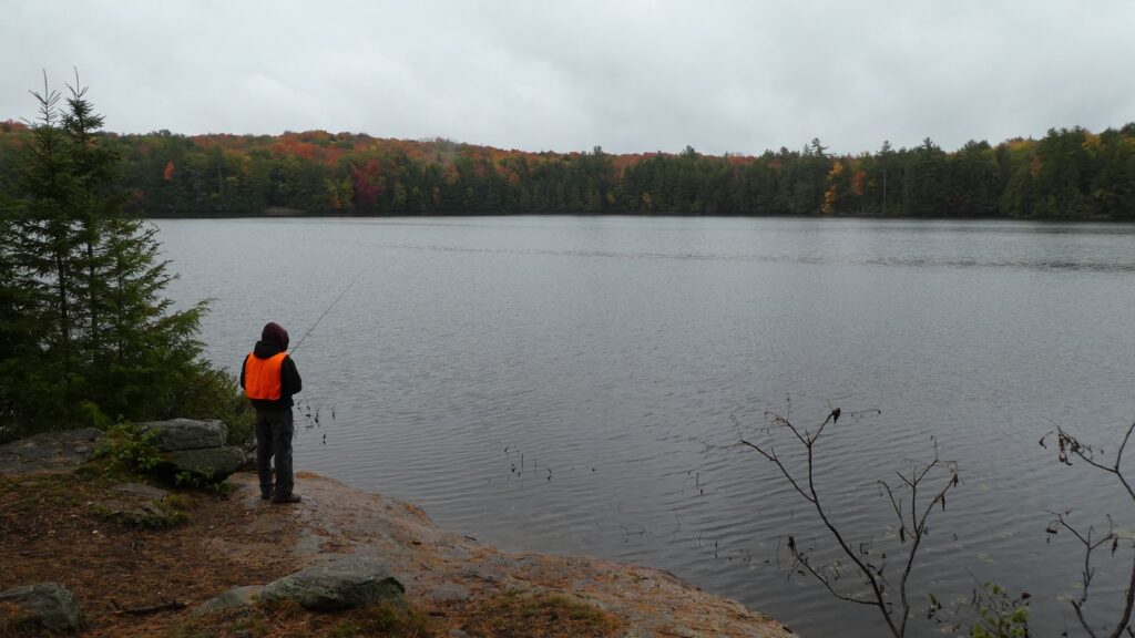 picture of a man fishing from shore while backcountry camping at Kawartha Highlands Provincial Park
