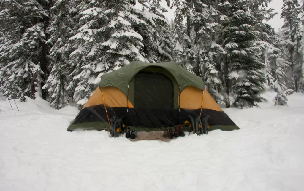 picture of a tent in the winter with snowy trees behind it